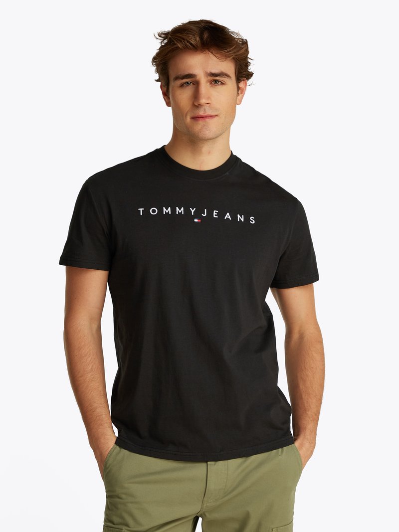 Fekete pamut póló fehér "TOMMYJEANS" logóval. Kerek nyakú, rövid ujjú design, olívazöld cargo nadrággal párosítva.