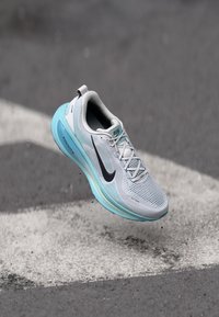 Svetlošedé bežecké tenisky s priedušným sieťovaným zvrškom, tyrkysovými akcentmi, čiernym logom swoosh a polstrovanou podrážkou.