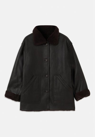 Veste en cuir noir avec col et poignets en shearling marron, dotée de fermetures à bouton sur le devant et de deux grandes poches latérales.
