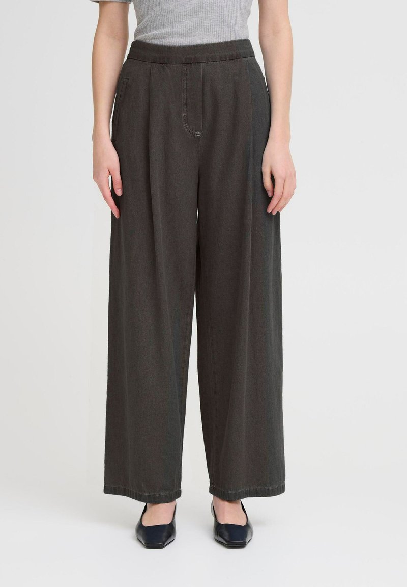 Pantalons larges, gris foncé, à taille haute, en denim. Comprend une poche avant avec des coutures subtiles et un ourlet soigné.