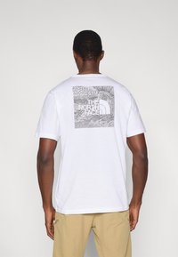 Λευκό βαμβακερό t-shirt με κοντά μανίκια, που φέρει μαύρο γεωμετρικό σχέδιο στην πλάτη, με το λογότυπο "THE NORTH FACE".