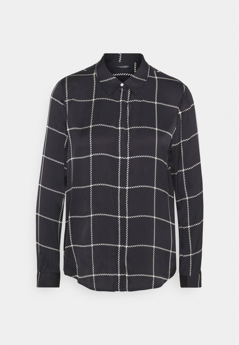 Chemise noire à manches longues avec boutons, motif quadrillé blanc et col pointu, présentée sur un fond gris clair uni.