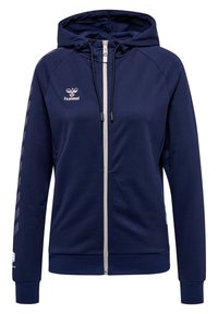 Marineblauwe zip-up hoodie gemaakt van zachte stof, met een witte rits, verstelbare capuchon en diagonale witte strepen op de mouwen.