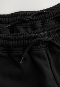 Musta verkkarit, jotka on valmistettu pehmeästä kankaasta ja joissa on joustava vyötärönauha kiristysnauhalla. Kangaspinta on sileä ja väri tasainen.