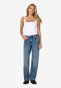 Λευκό κορμάκι με τετράγωνη λαιμόκοψη συνδυασμένο με ανοιχτό γαλάζιες φαρδιές τζιν. Τα τζιν διαθ�έτουν κλασικό σχέδιο πέντε τσεπών και ελαφριά ξεθώριαση.