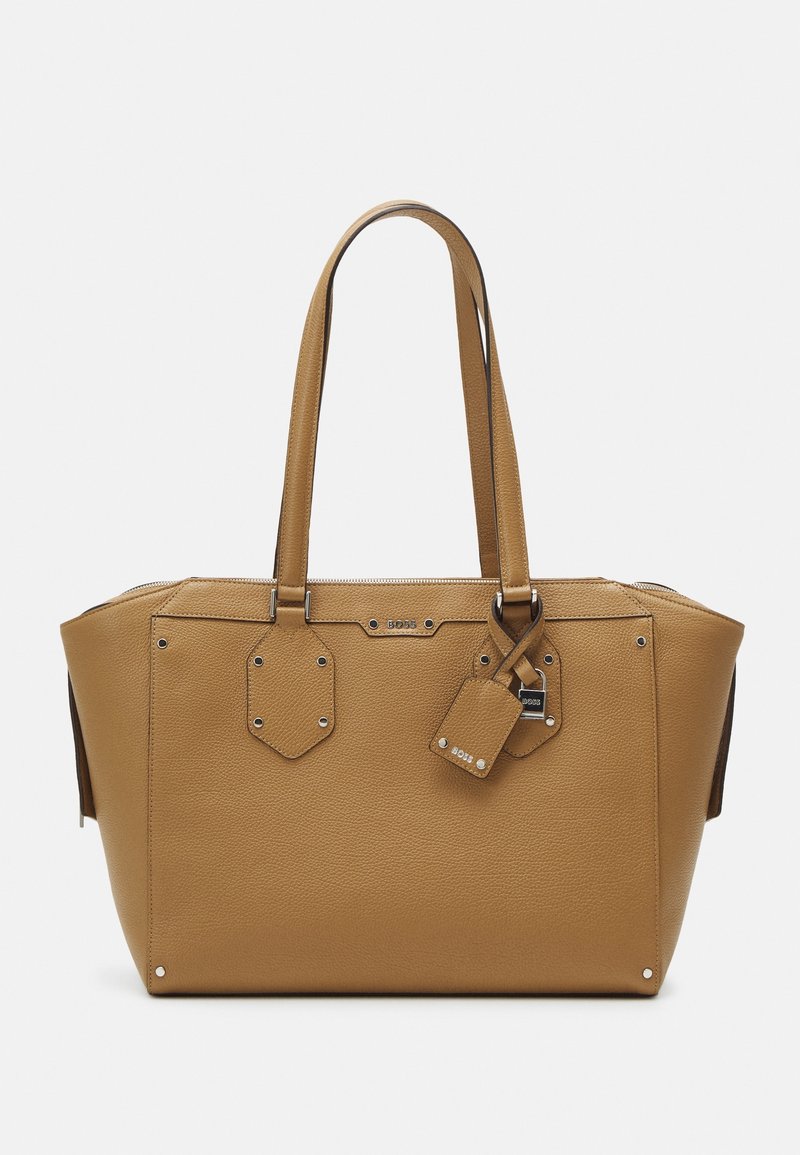 Brązowa torba na ramię ze skóry, z podwójnymi uchwytami, zamknięciem na zamek, sześciokątnymi ozdobami i odpinaną metką. Faktura powierzchni z srebrnymi elementami metalowymi.