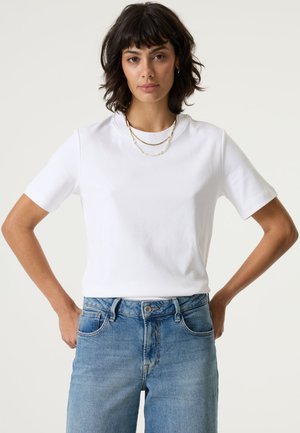 White cotton t-shirt with short sleeves and a round neckline, paired with light blue denim jeans. Flat texture and casual fit.