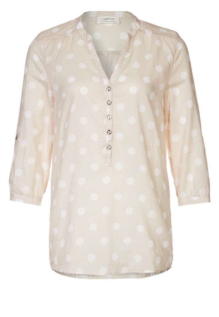 Blusa beige chiaro con pois bianchi, maniche a tre quarti, abbottonatura con bottoni rotondi, tessuto morbido, vestibilità comoda, orlo curvo.