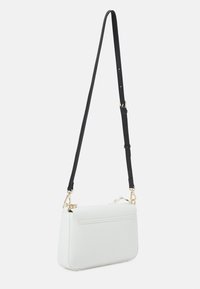 Weißes Leder-Crossbody-Bag mit strukturierter Form, schwarzem verstellbarem Tragegurt und goldenen Hardware-Akzenten. Glatte Textur und minimalistisches Design.