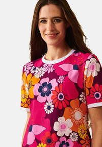 Lyhythihainen kukkatoppi, jossa on kirkkaan vaaleanpunaisen, oranssin ja purppuran värisiä kukkia. Pyöreä kaula-aukko valkoisella reunuksella, valmistettu pehmeästä kankaasta.