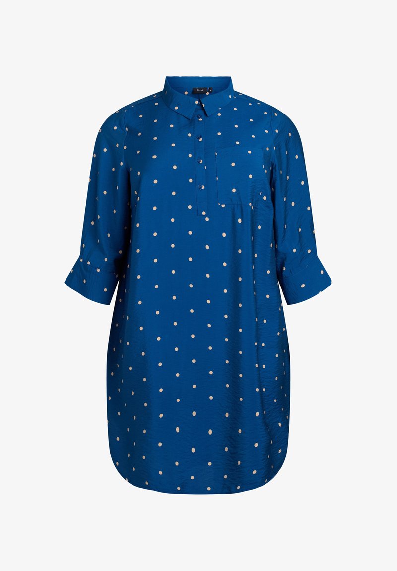 Niebieska tunika w kropki z kołnierzykiem, rękawami o długości trzech ćwiartek, kieszenią z przodu i lekko zaokrąglonym dołem. Wykonana z gładkiego, lekkiego materiału.