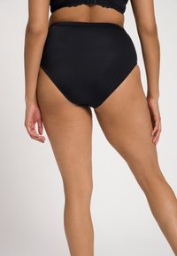 Mutande bikini nera a vita alta realizzata in tessuto morbido ed elastico. Presenta un design senza cuciture e una forma classica che si adatta al corpo.