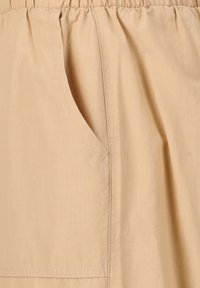 Hame beige, jossa on kerätty vyötärö ja sivutasku. Sileä pinta, jossa on minimaalinen ompelutaito. Kevyt kangas, joka sopii rentoon käyttöön.