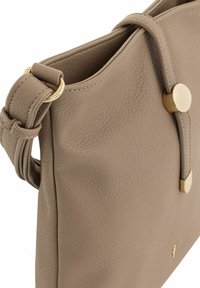 Beżowa skórzana torebka o teksturowym wykończeniu, z złotymi akcentami, węzłowym paskiem i zapięciem na magnes. Prosty, elegancki design.