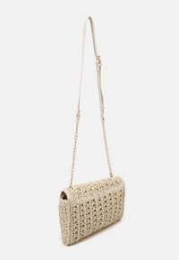 Tkana torebka w naturalnym kolorze o usztywnionym kształcie, wyposażona w złoty łańcuchowy pasek i fakturowane wykończenie. Zamknięcie u góry z zaokrąglonymi krawędziami.