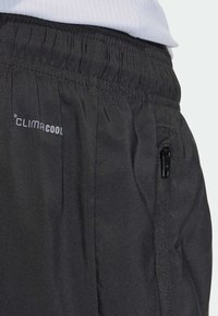 Schwarze Sportschorts mit ClimaCool-Logo, elastischem Bund und einer kleinen Reißverschlusstasche an der Seite. Glatter, leichter Stoff.
