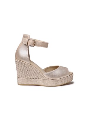 Sandali na platformo z zgornjim delom iz metalno zlate barve, odprtim prsti, trakcem okoli gležnja ter podplatom iz tkanega juta. Ima gladko teksturo in višino pete 7,5 cm.