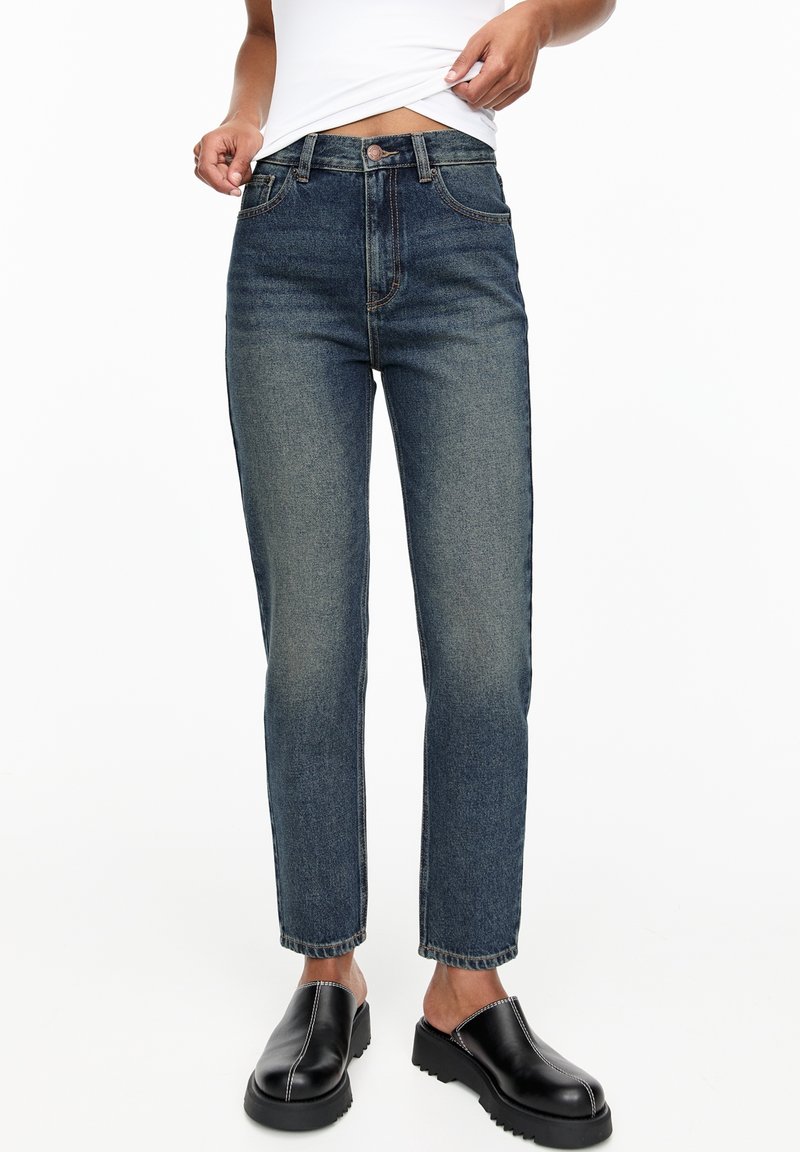 High-waisted blue jeans in a dark denim wash with a straight-leg cut, featuring contrast stitching and a button closure at the waistband.