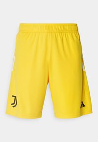 Pantalones cortos deportivos amarillos con cintura elástica, que cuentan con logotipos negros y acentos laterales blancos. Hechos de una tela ligera y suave.
