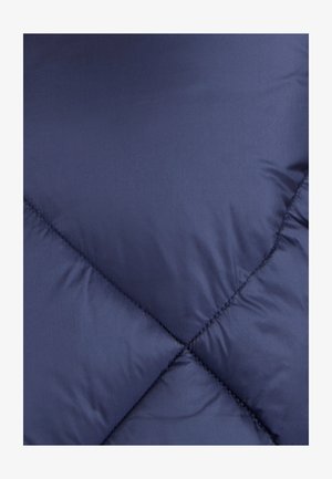 Tissu d'une veste matelassée bleu marine, avec un motif matelassé diagonal et une texture lisse et brillante, présentant des détails de couture visibles.