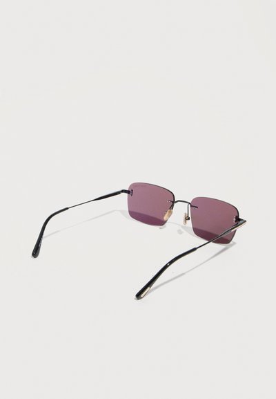 Square-shaped sunglasses with thin black metal frames and purple tinted lenses resting on a white surface.