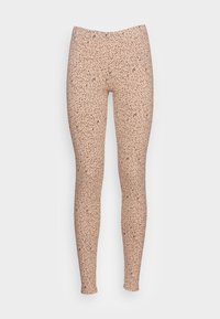 Leggings bege com um padrão negro salpicado, feitos de material elástico, com uma textura suave e um design ajustado.