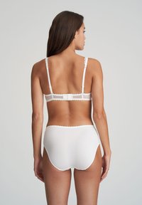 Set di lingerie bianco composto da un bralette con rifiniture in pizzo e mutandine a vita alta in tessuto morbido e design semplice. Inclusi spallini regolabili.