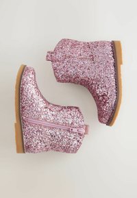 Rosa glittrande ankelskängor med en slät yta, sidodragkedjestängning och en brun gummisula. Glittrande yta täcker hela ytan.