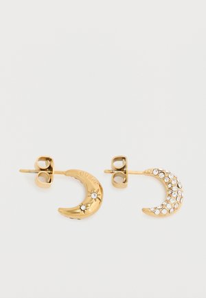 Kultaiset puolikuun muotoiset nappikorvakorut; toinen yksinkertainen, jossa kaksi pientä strassikiveä, toinen peitetty useilla kirkkailla strassikivillä, molemmissa perhonsuljenta.