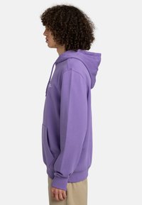 Felpa viola con tasca frontale e cappuccio con cordino, realizzata in tessuto morbido. Presenta polsini a costine e una vestibilità comoda.