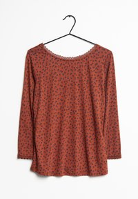 Långärmad rostfärgad topp med blått blommönster, vågig halsringning och ärmslut. Tillverkad av mjukt tyg med en avslappnad passform och rundad nederkant.