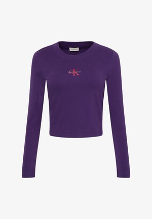 Lila Crop-Top mit langen Ärmeln aus Baumwolle, verfügt über ein kleines rotes Logo auf der Brust, einen runden Ausschnitt und eine gerippte Textur.