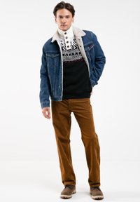 Denim jope, millel on lamba nahast krae, musta mustriga sviiter ja pruunid corduroy püksid. Sisaldab pruune saapaid, millel on heledat värvi tallad.