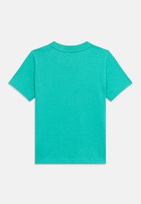 Απλό τιρκουάζ κοντομάνικο μπλουζάκι με στρογγυλή λαιμόκοψη, απλωμένο επίπεδα με την πίσω πλευρά στραμμένη προς τα πάνω σε λευκό φόντο.