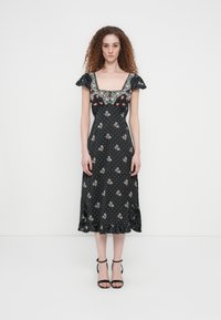 Μαύρο φόρεμα με λουλουδένιο μοτίβο, τετράγωνο ντεκολτέ, κοντά μανίκια με βολάν, μοτίβο πουά και βολάν στο τελείωμα. Συνδυασμένο με μαύρες πεδιλοφόρες γόβες με λουράκια.