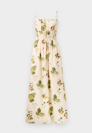 Maxi dress in pale beige fabric with green and orange fruit and leaf patterns. Features adjustable straps and a smocked waist for shape.