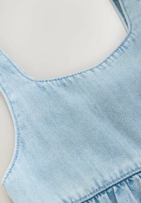 Tirantes delgados de denim azul claro, con una textura suave y sutil costura vertical, adornado con detalle de recogido en la parte inferior.