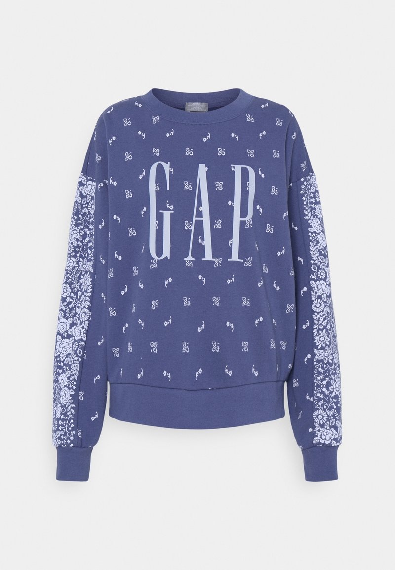 Sudadera azul con pequeños estampados florales blancos, patrones florales más grandes en las mangas y gran texto "GAP" en la parte frontal.