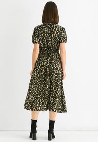 Leopard print midi dress with short puff sleeves, elastic waist, and flared skirt, made from a lightweight fabric. Black ankle boots paired.