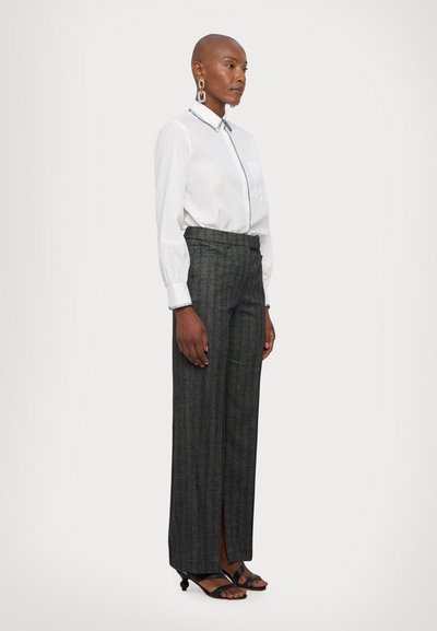 White button-up shirt with contrasting collar trim and gray striped high-waisted trousers featuring a side slit. Black heeled sandals.