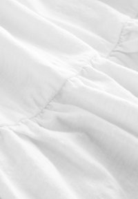 Tela blanca con una superficie suave y texturizada con pliegues que crean pliegues delicados. El material parece ligero y aireado.