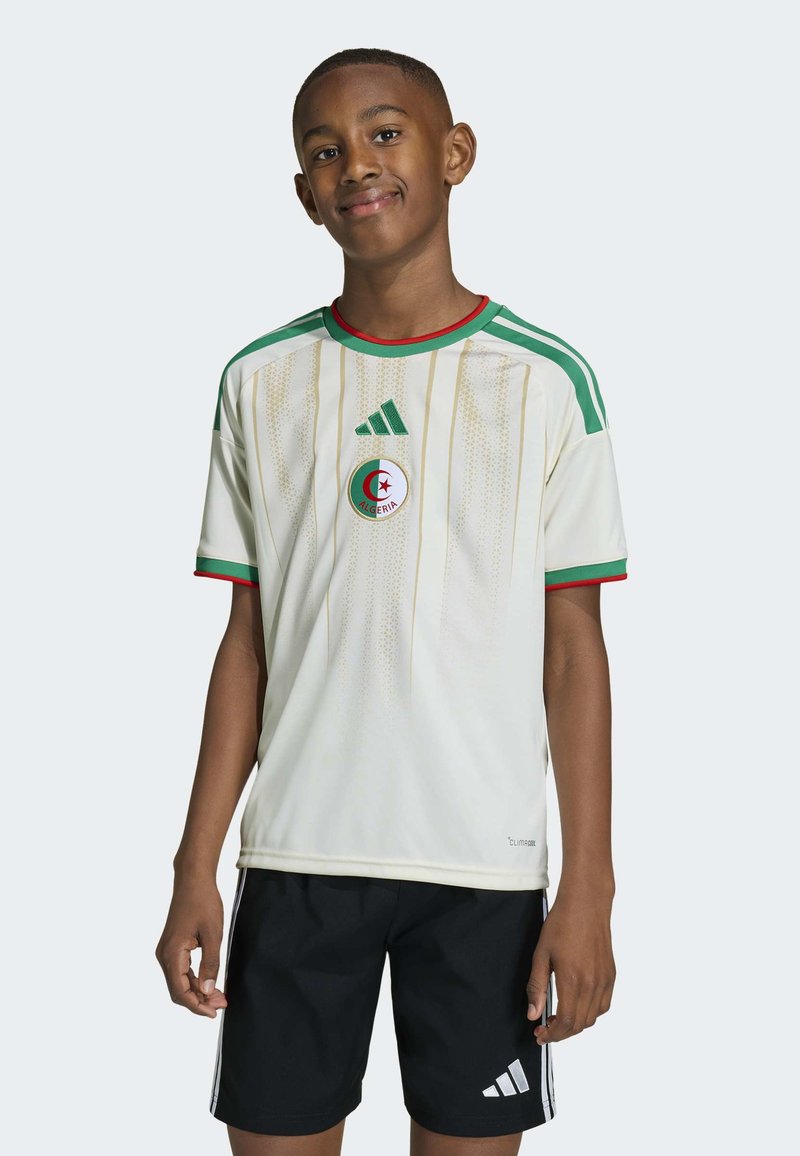 Maillot de football blanc avec des accents verts et une bordure rouge, arborant le logo de l'équipe nationale algérienne et un motif de rayures verticales. Porté avec un short noir.