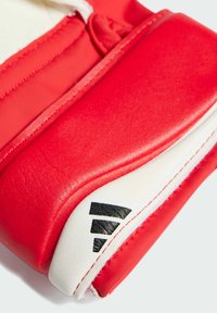 Rode leren sporthandschoen met witte accenten, voorzien van een textuur en zwarte logo-details. Gestikte randen verhogen de duurzaamheid.