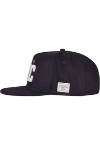 Căciulă albastră închis, cu vizor plat, cu litere albe ridicate. Prezintă un etichetă rectangulară cu logo-ul "CAYLER & SONS" pe lateral. Fabricată din material textil.