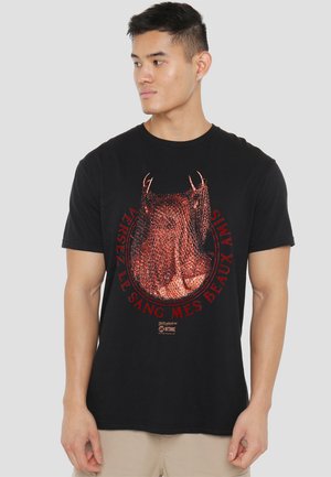Black cotton t-shirt featuring a metallic red graphic of a bull skull with text. Round design with short sleeves and a crew neck.