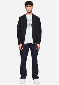 Dunkelgrauer Cardigan mit Knopfleiste, strukturiertem Strick und gerippten Bündchen, getragen über einem hellblauen Grafik-T-Shirt und dunklen Jeans.