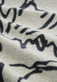 Tela texturizada en beige y gris oscuro, con líneas y patrones abstractos. Material suave, parecido a la lana, con un ligero brillo.
