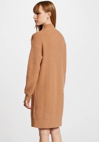 Langærmet, hoge hals gebreide sweater jurk in lichtbruin, met een textuur afwerking en ribbeldetails op de halslijn en manchetten.