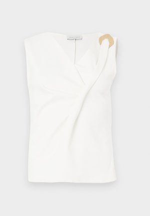 Bezrukávová bílá blůza s překříženým designem, která má zlatý dekorativní kroužek na pravém rameni.