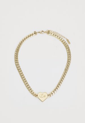 Gullkjede med sammenkoblede lenker, hjerteformet anheng med logo, og forlengerkjede for justerbar lengde.